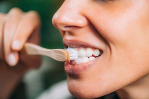 Woman brushing teeth with toothbrush, showcasing effective teeth whitening routine at home, relevant to cosmetic dentistry and oral health.